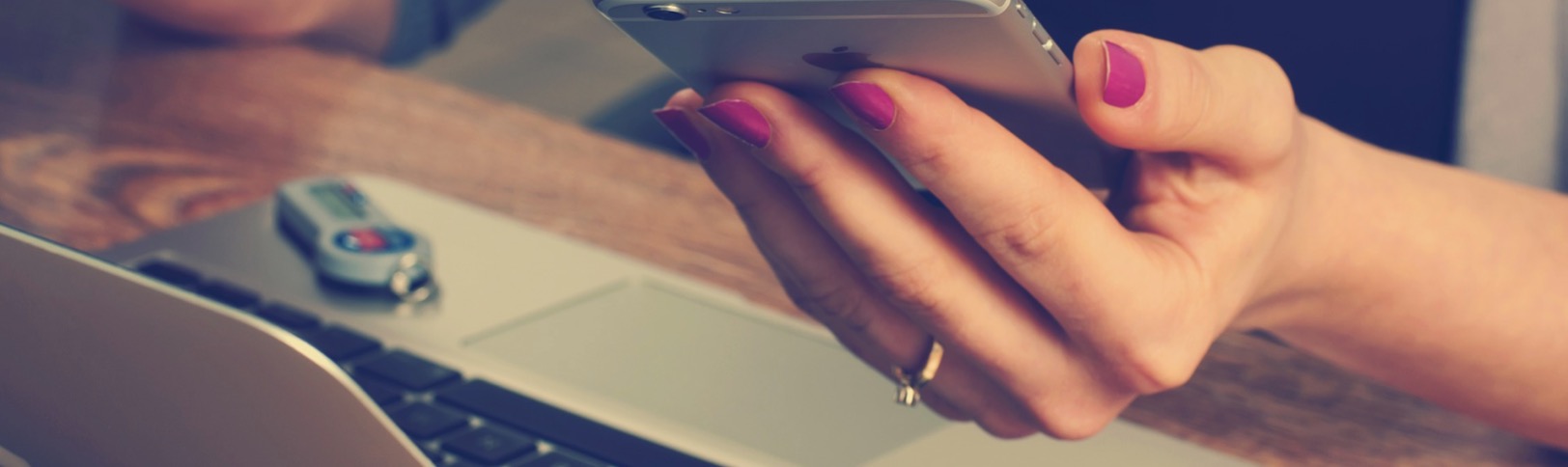 Smartphone en main au-dessus d'un ordinateur
